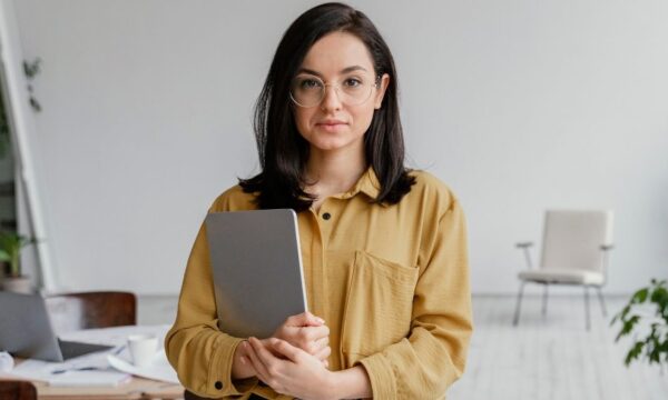 Uma mulher segurando um tablet em um escritório.