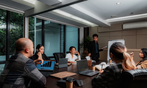 Reunião de equipe em sala corporativa, com profissionais analisando indicadores e discutindo processos para implementação de um Sistema de Gestão Integrado em ambiente empresarial.